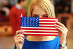 Portrait of a student peeking behind flag of USA